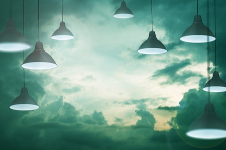 Many lamps in the stormy moody cloudy sky as a symbol and concept of energy saving creativityの写真素材