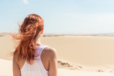 Beautiful young woman wearing sunglasses in desert sand dunesの写真素材