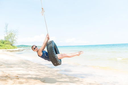 Happy woman having fun on tire swing at the beach. Phu Quoc, Vietnamの写真素材