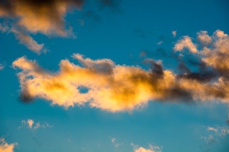 Puffy and colorful sunset clouds closeup over blue sky