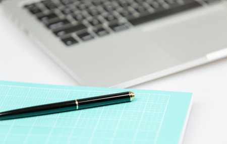 Laptop pc with pen and notebook in foregorund. pc out of focus