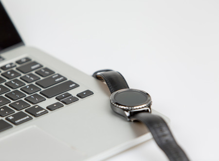 smartwatch on top of a laptop. smartwatch on standby, focus on keyboard. studio shot on a white backgroundの写真素材