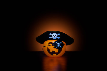 A studio isolated Jack O'lantern is decorated as a pirate and cast in eerie light for Halloween.の写真素材