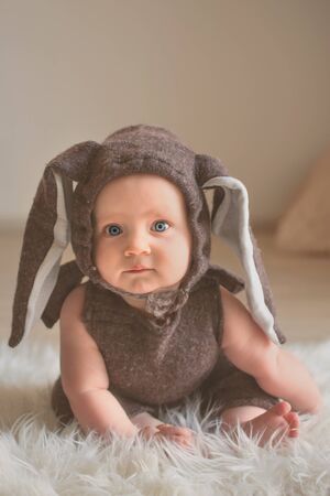 little baby in easter bunny costumecute, baby in bunny dress sitting on furry blanketの写真素材