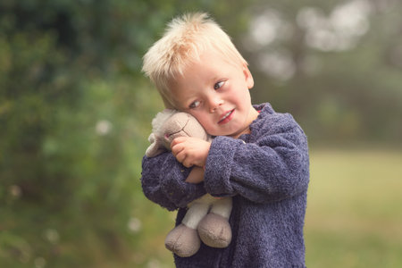 Little boy is playing with plush sheep, boy with plush toy on green grassの写真素材