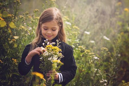 young girl with flowers in her hands standing in the natureの写真素材