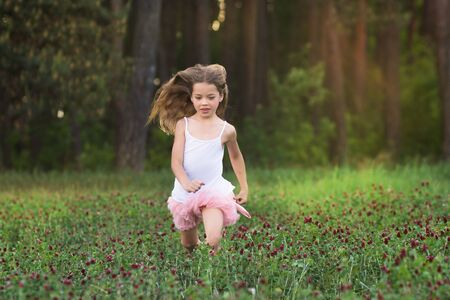 pretty young girl is running on meadow with red flowersの写真素材