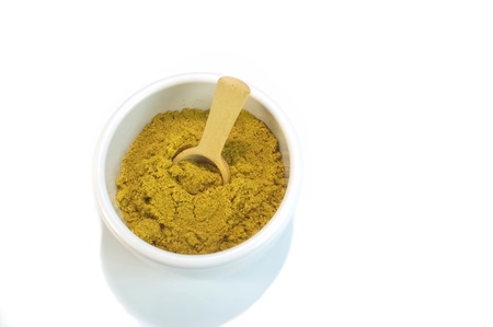 Curry powder in small container with wooden spoon for cookingの写真素材