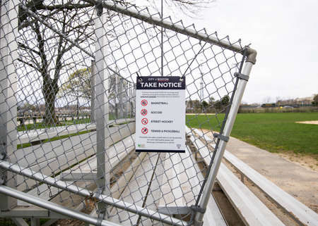 Sign on park bench announcing closure to prevent spread of Coronavirus in Boston