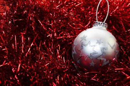 Silver Christmas bulb sitting on a red metal background.の写真素材