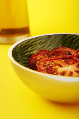 Dried sliced tomatoes in green bowl on the yellow background.の写真素材