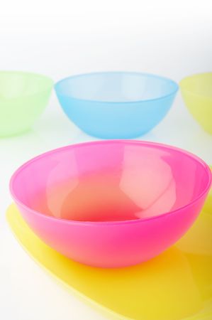 Four colored plastic vases on reflective white background