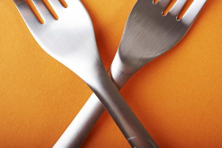Two crossed forks over a orange backgroundの写真素材
