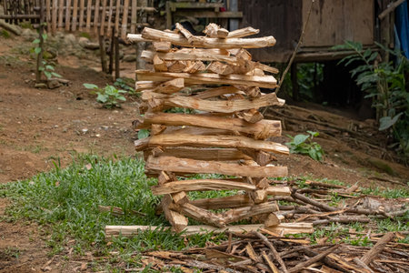 Freshly cut stacked firewood in front of a wooden house. Chopped firewood used for cooking in an outdoor kitchen.の写真素材
