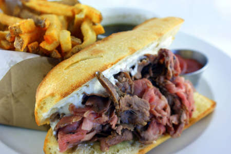 French Dip Sandwich - Juicy smoked prime rib sandwich on a crunchy French baguette smeared with horseradish sauce, and thinly sliced medium rare prime rib and Swiss cheese の写真素材
