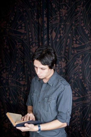 Young turkish guy reading book on the studio backgroundの写真素材