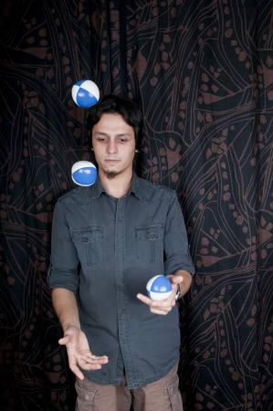 Young turkish guy playing juggling balls on black backgroundの写真素材