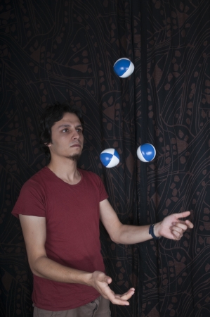 Young turkish guy playing juggling balls on black backgroundの写真素材