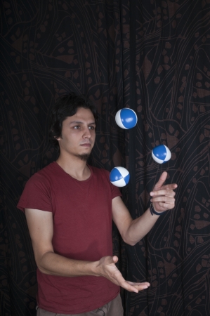 Young turkish guy playing juggling balls on black backgroundの写真素材