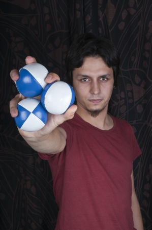Young turkish guy holding juggling balls on black backgroundの写真素材