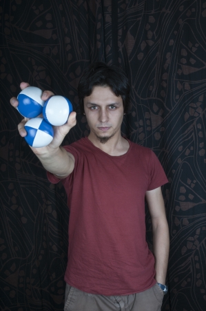 Young turkish guy holding juggling balls on black backgroundの写真素材