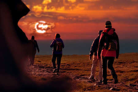 people reach the top walking at sunsetの写真素材