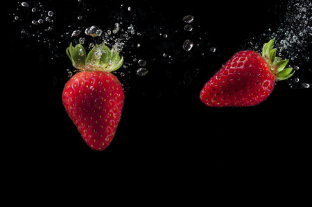 two strawberries splashing in waterの写真素材