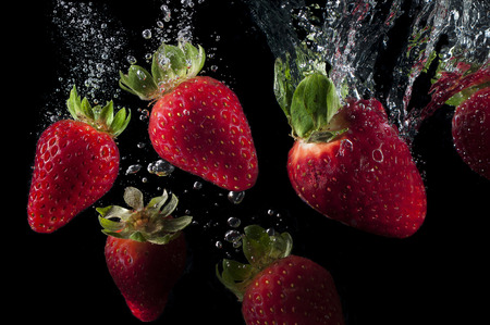 strawberries falling in waterの写真素材