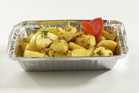 Indian dish fried potato with cumin in metal foil tray.の写真素材