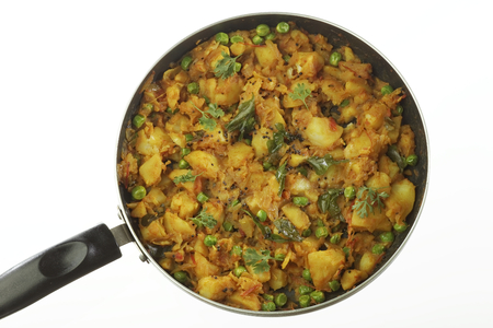 Cooked spicy potato preparation with other vegetables like onion and green peas.の写真素材