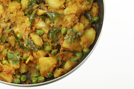 Cooked spicy potato preparation with other vegetables like onion and green peas.の写真素材