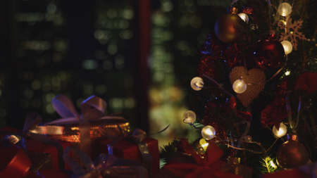 New Years Christmas festive background with the night city outside the window. Christmas tree. Decorations, red gold balls and glowing bulbs on the tree. Warm home mood. Depth of field, soft focusの写真素材