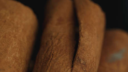 Cinnamon sticks on a dark background. Spicy cinnamon seasoning for baked goods, fruit desserts, puddings and drinks. Extreme close-up, macro viewの写真素材