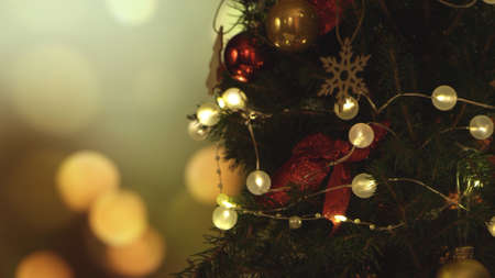 New Years Christmas festive background with lights on the background. Christmas tree. Decorations, red gold balls and glowing bulbs on the tree. Warm home mood. Depth of field, soft focusの写真素材