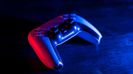 Moscow, Russia - March 8 2021: Gamepad (joystick) on a pink-blue background of synthetic glass of...