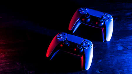 Moscow, Russia - March 8 2021: White gamepads on a wooden table. Two controller joysticks. Sony...