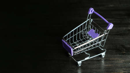 Shopping Cart. Mini shopping trolley on dark wooden background. Mini Shopping Cart On The Table. Business, e-commerce conceptの写真素材