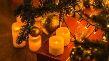Christmas and New Year interior decoration. Green tree decorated with toys, gifts, present boxes, candles. Xmas tree. Cozy christmas atmosphereの写真素材