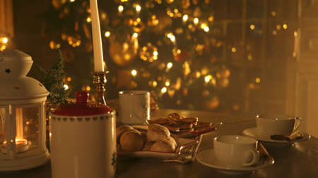 Christmas table. Served dishes. Candles, mugs, baked goods, cinnamon. Christmas tree and fireplace...