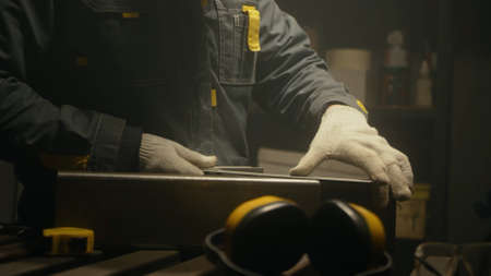 Metalworker in the workshop makes measurements with ruler, calculations and puts serifs with chalk....