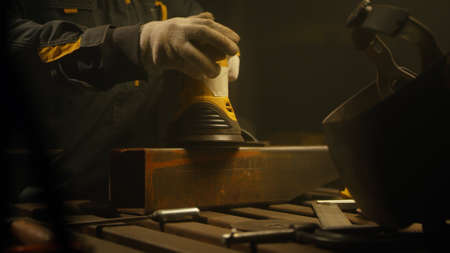 Worker polishing metal with grinder. Interior of a heavy industry factory with a worker using a...