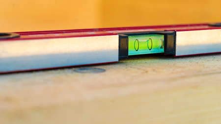 Magnetic level with gauge capsule on wooden surface macro view. Professional construction tool....