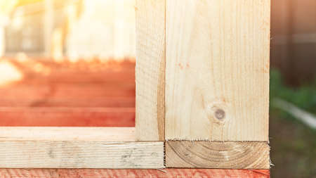 Connection of textured wooden boards at construction site closeup. Traditional technology of building assembly. Right angle of frame cornerの写真素材