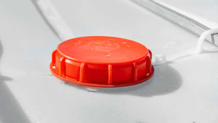 Red plastic cap on large bulk container extreme closeup. Scratched lid of canister for liquid products. closed water tank. industrial equipmentの写真素材