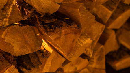 Firewood heap of natural timber in semi-dark room closeup. Dry woodpile stack prepared for domestic...