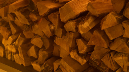 Firewood heap of natural timber in semi-dark room closeup. Dry woodpile stack prepared for domestic fireplace burning at home. Chopped lamb stock for fireside in house at warm lightの写真素材