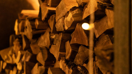 Firewood heap of natural timber in semi-dark room closeup. Dry woodpile stack prepared for domestic fireplace burning at home. Chopped lamb stock for fireside in house at warm lightの写真素材