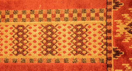 Decorative carpet with color patterns as background upper view. Vintage natural rug decorated with symmetrical ornament closeup. Handmade textile covering for home interior designの写真素材