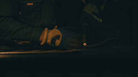 A man works with a welding machine at a factory. A welder welds metal in a workshop. Sparks fly from...