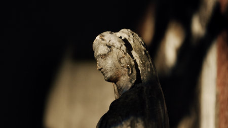 Portrait of an antique old statue on the background of a stone wall. Impressive Gothic sculpture in...